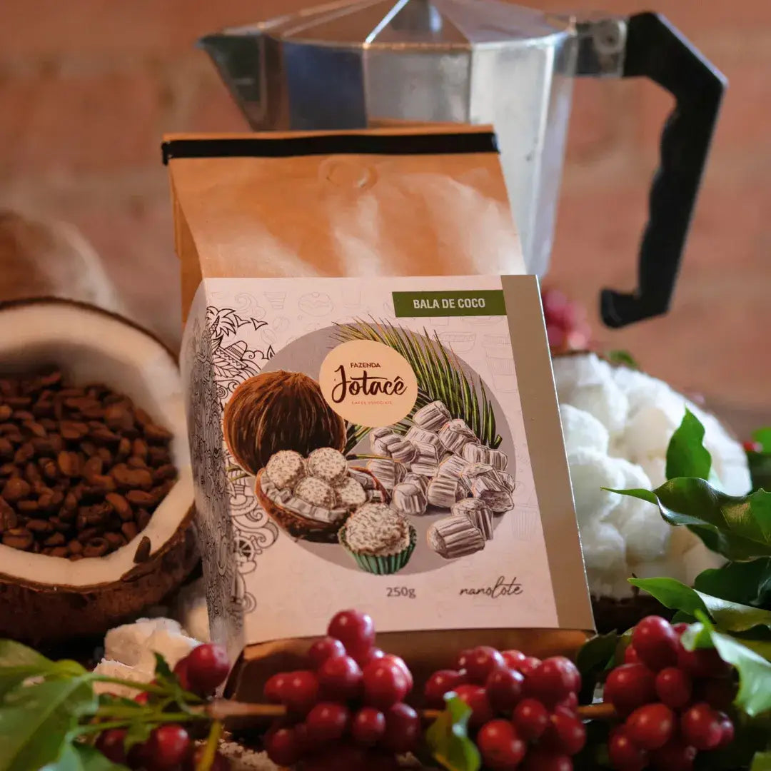 Café Bala de Coco da Fazenda Jotacê ao lado de grãos de café, cocos e utensílios de preparo, em composição natural e rústica.