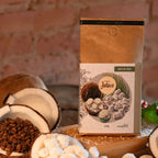 Café Bala de Coco da Fazenda Jotacê exposto ao lado de grãos de café e pedaços de coco, evidenciando os aromas e sabores naturais do produto.