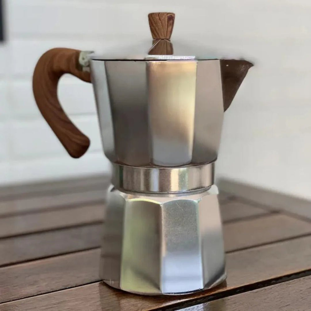 Cafeteira Italiana de 300 mililitros com alça de madeira da mimo style sobre mesa de madeira com fundo desfocado