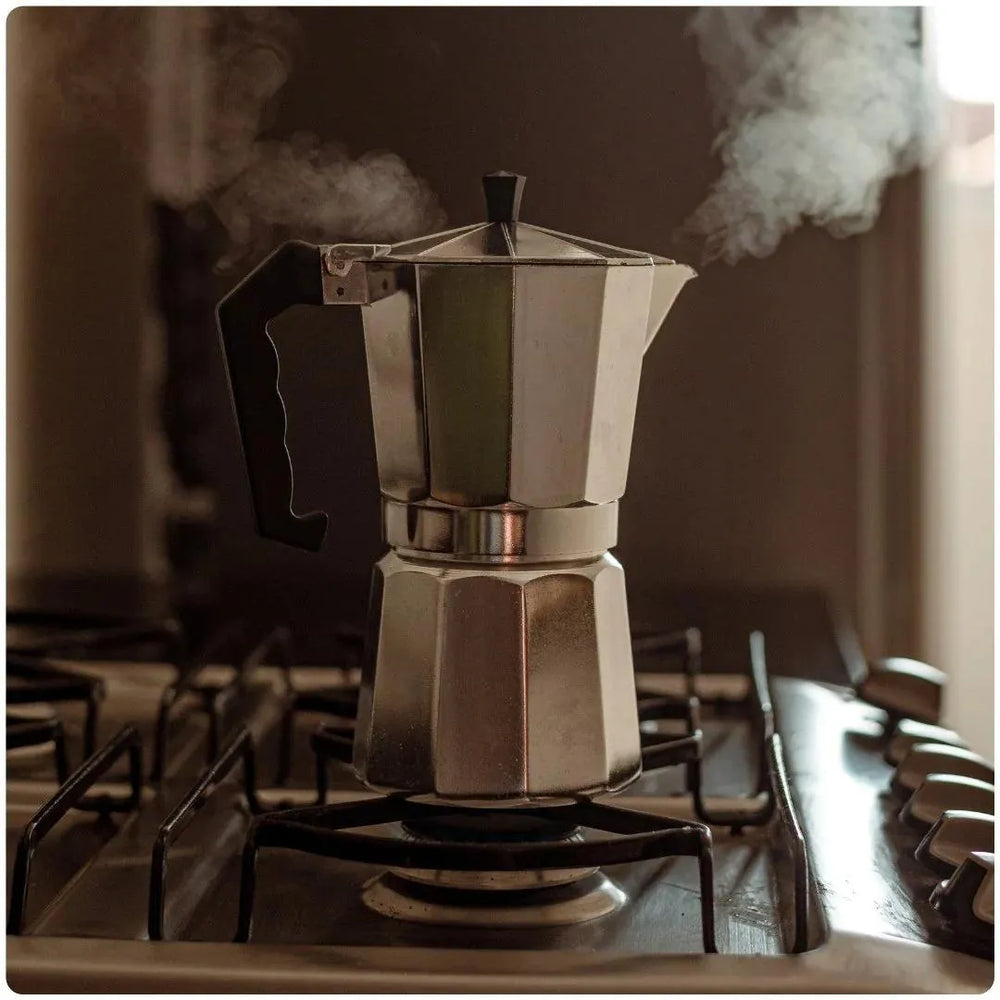 Cafeteira italiana de 450 mililitros de alça preta da mimo style soltando vapor ao extrair café em cima de fogão
