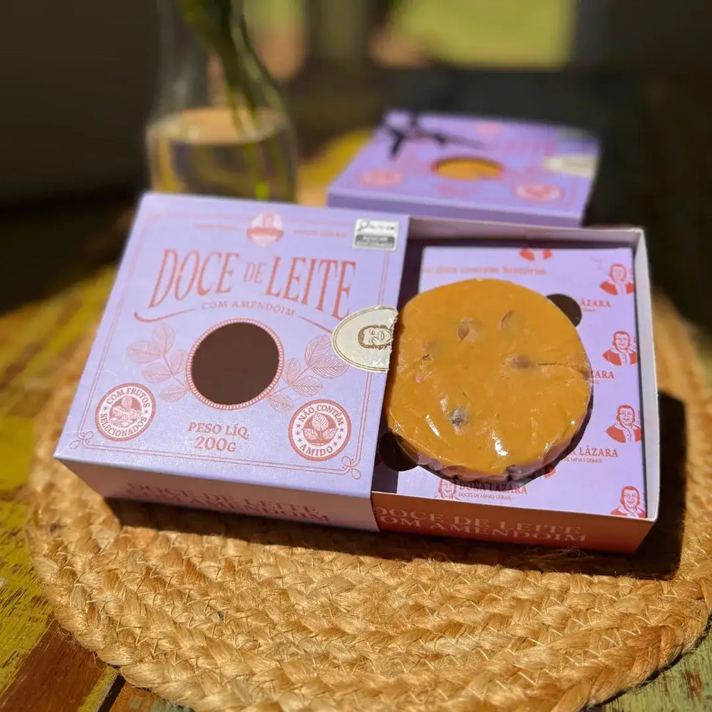 Doce de leite com amendoim parcialmente exposto na caixa gaveta, com embalagem Dona Lázara ao fundo.