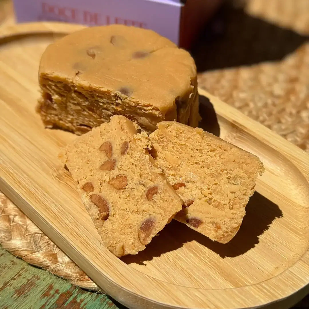 Doce de leite de corte com amendoim fatiado sobre bandeja de madeira, mostrando a textura firme e os pedaços de amendoim.