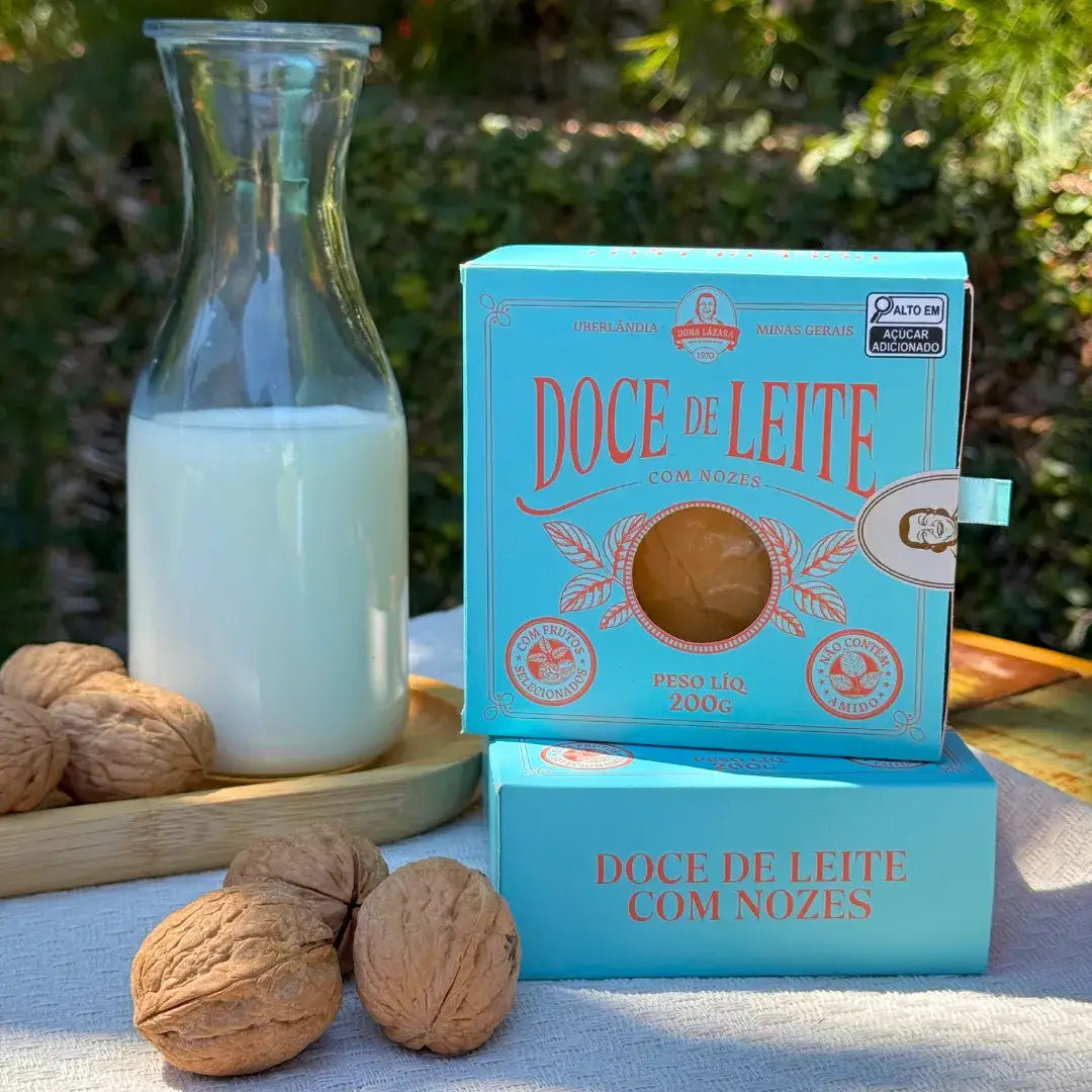 Empilhamento de duas caixas de Doce de Leite com Nozes Dona Lázara ao lado de garrafa de leite e nozes, em ambiente ensolarado, destacando o design artesanal.