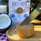Faca cortando o Doce de Leite com Coco Dona Lázara, revelando a consistência macia e o brilho natural do leite fresco e do coco.