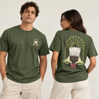 Dois modelos vestindo a camiseta verde militar, um de frente mostrando a estampa pequena no peito e outra de costas com a estampa grande do copo de café coado, arco de sol e ramo de café com frutos vermelhos.