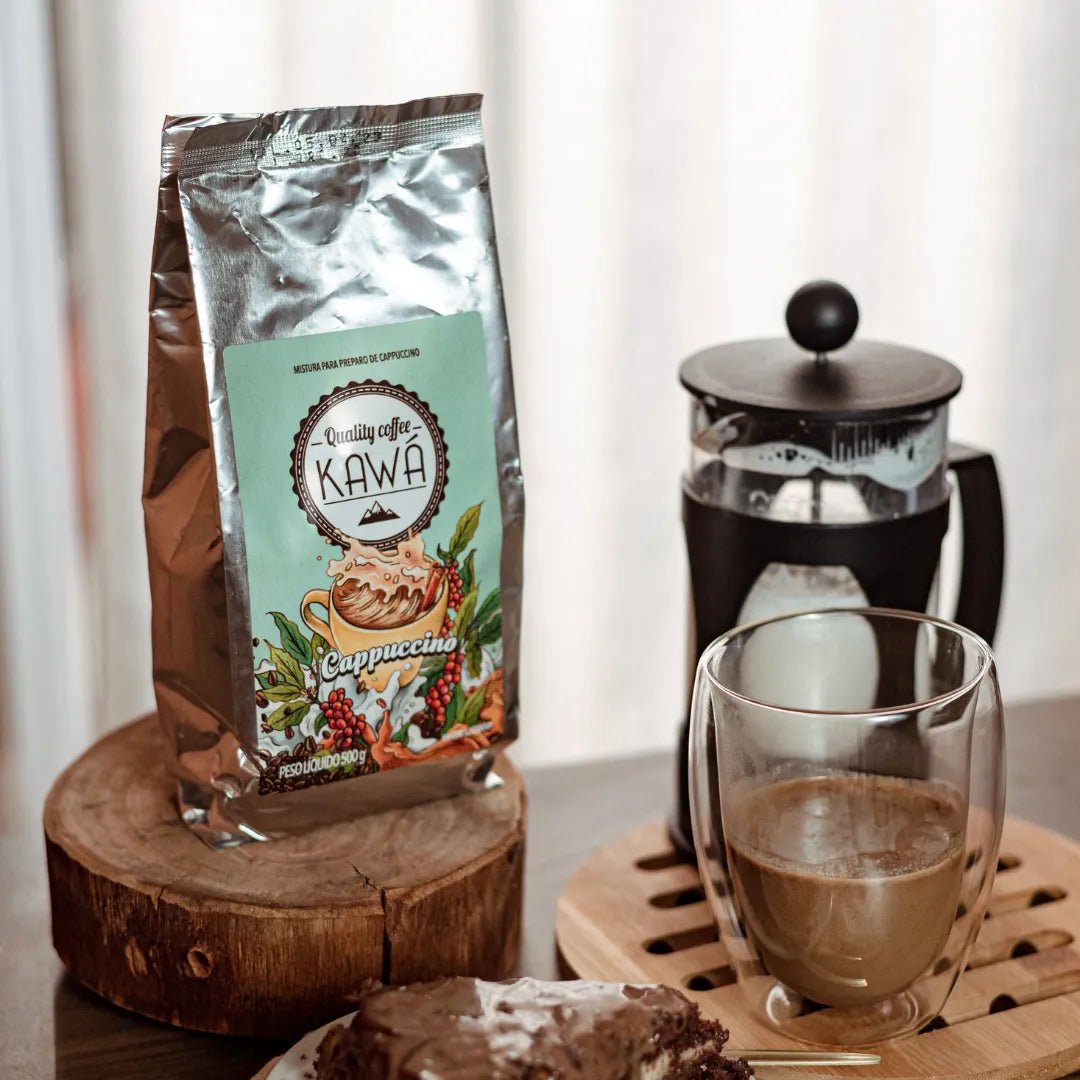 Xícara e Pacote de Cappuccino Kawá da Fazenda Jotacê com bolo de chocolate e prensa francesa preenchida de leite sobre mesa
