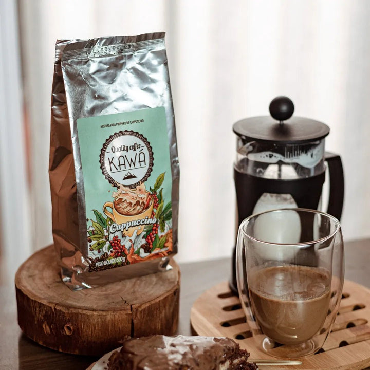 Xícara e Pacote de Cappuccino Kawá da Fazenda Jotacê com bolo de chocolate e prensa francesa preenchida de leite sobre mesa