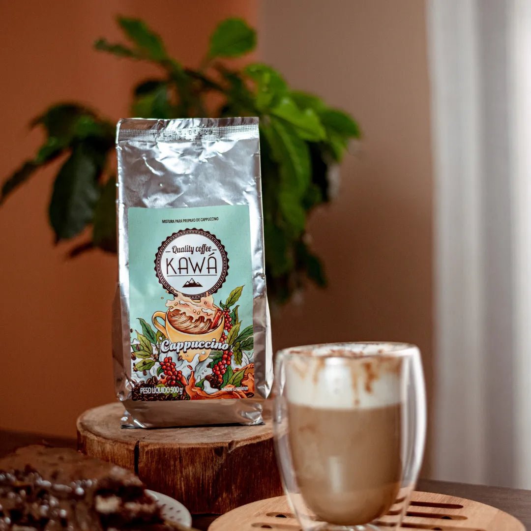 xícara e pacote de Cappuccino Kawá da Fazenda Jotacê com bolo de chocolate e planta ao fundo desfocados