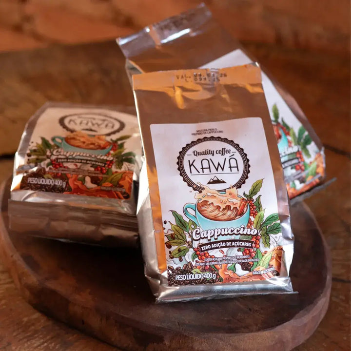 Três embalagens do Cappuccino Kawá Zero Açúcar dispostas sobre tábua de madeira rústica, em cenário acolhedor e artesanal.