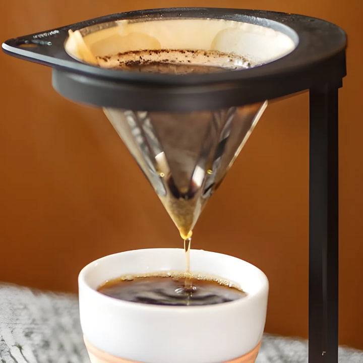 Close-up do SoloUno com café filtrando diretamente no copo de cerâmica.