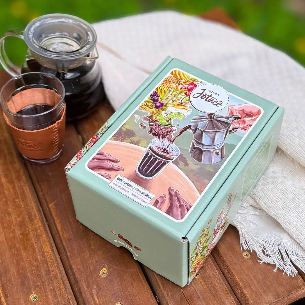 Caixa da Coleção Origens da Fazenda Jotacê exibindo ilustração colorida de moka despejando café em copo lagoinha.