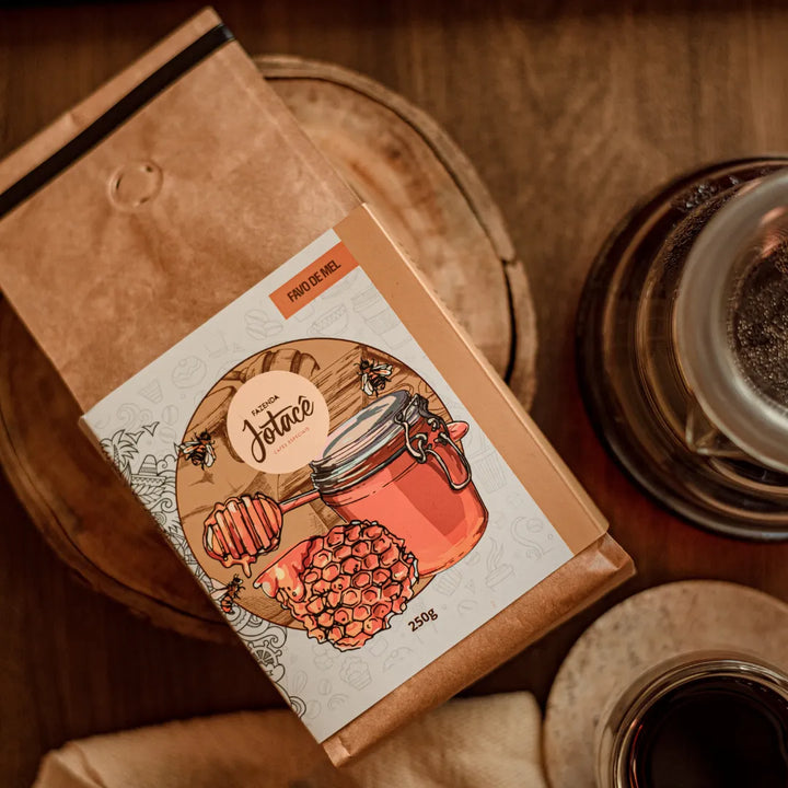 Pacote de café Favo de Mel da Fazenda Jotacê sobre tábua rústica de madeira em ambiente rústico