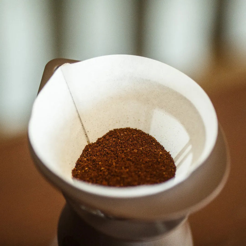 Filtro de café cônico com pó fresco pronto para a infusão, close-up.