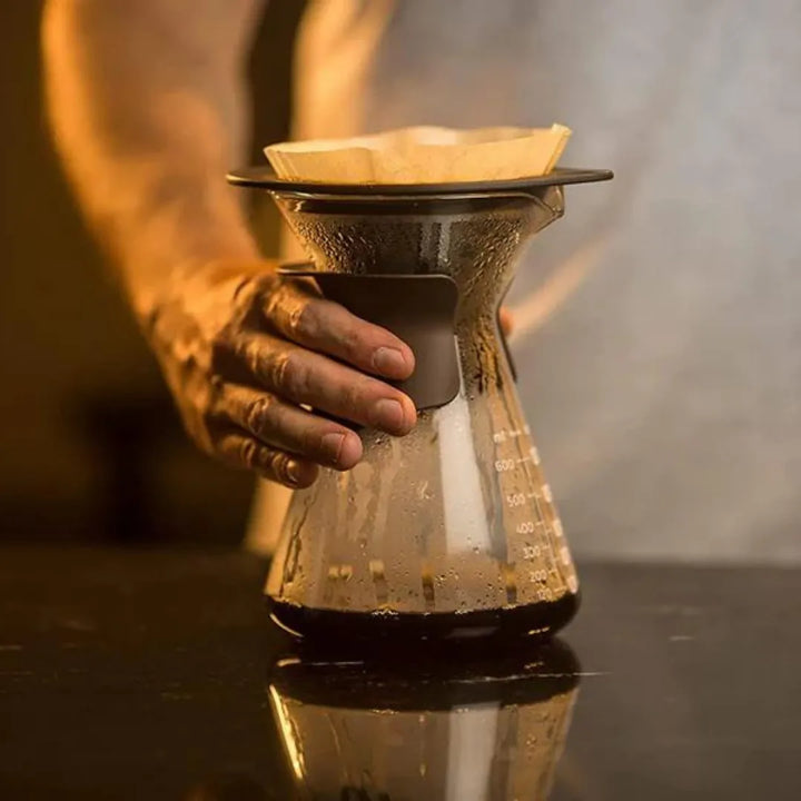 a mão de uma pessoa segurando o kit fluire durante a extração do café quentre sobre uma mesa