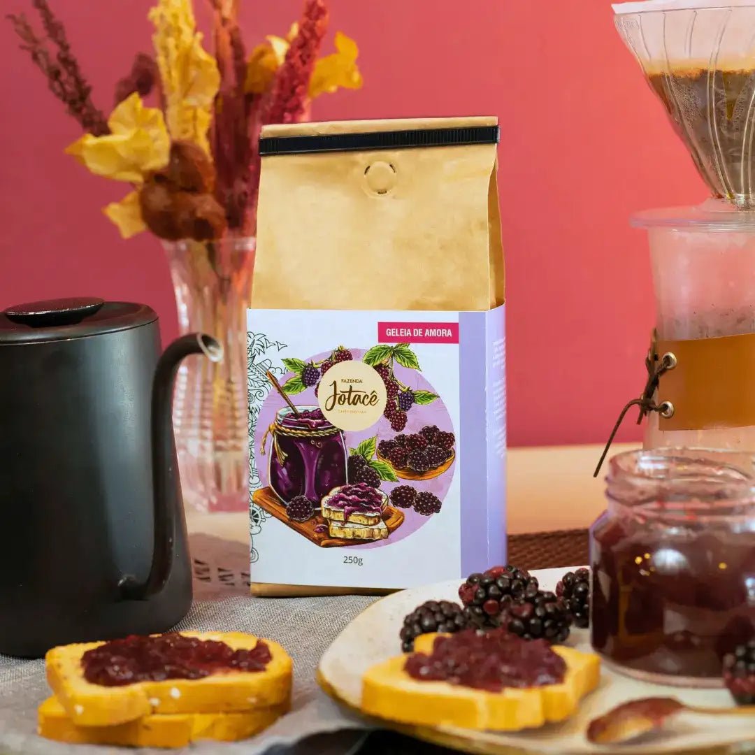 Café Especial Geleia de Amora da Fazenda Jotacê ao lado de fatias de pão com geleia, café coado e frutas frescas, remetendo a um café da manhã aconchegante e cheio de sabor.