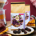 Detalhe do Café Especial Geleia de Amora da Fazenda Jotacê em embalagem de 250g, com ilustração de amoras e mel, acompanhado de frutas frescas e um café coado para uma experiência sensorial completa.