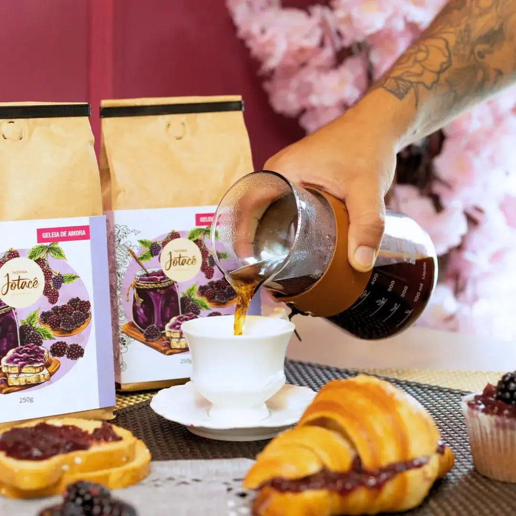 Cena de café da manhã com Café Especial Geleia de Amora da Fazenda Jotacê, croissant recheado e café sendo servido em uma xícara, destacando notas sensoriais de amora, mirtilo e mel.