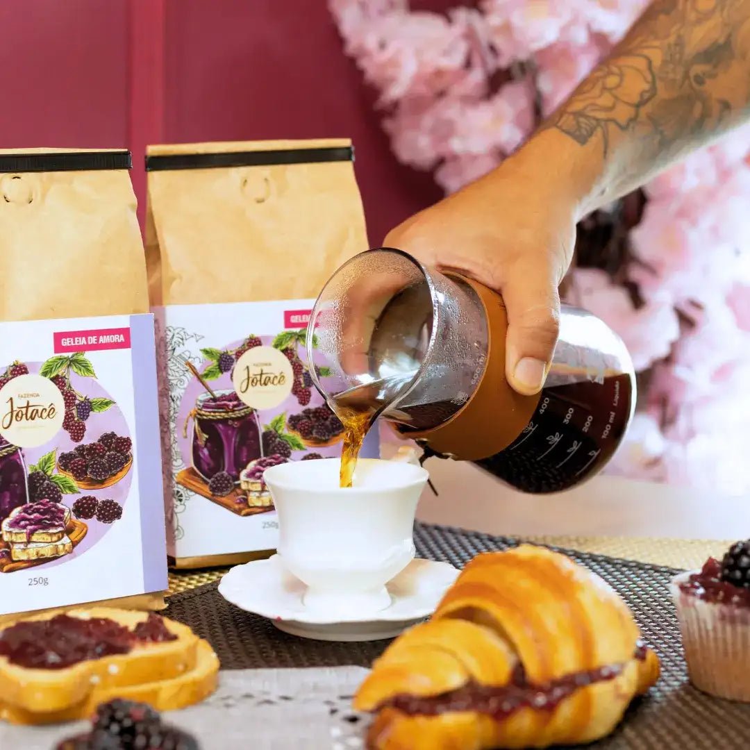 Cena de café da manhã com Café Especial Geleia de Amora da Fazenda Jotacê, croissant recheado e café sendo servido em uma xícara, destacando notas sensoriais de amora, mirtilo e mel.