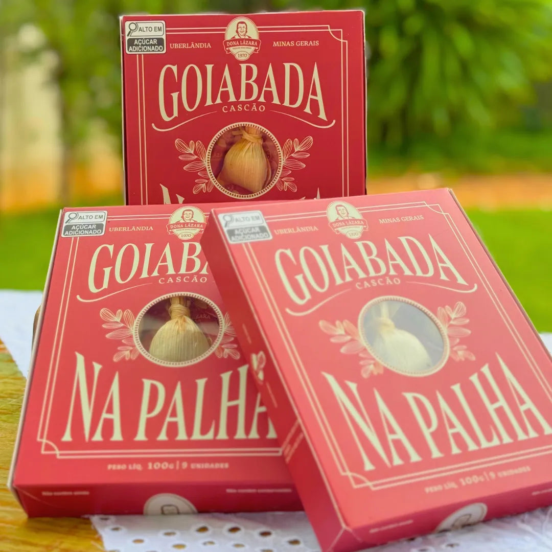 Três caixas vermelhas de Goiabada Cascão na Palha Dona Lázara empilhadas em cenário de jardim, com visor circular no centro mostrando doce em palha de milho, marca de Uberlândia MG