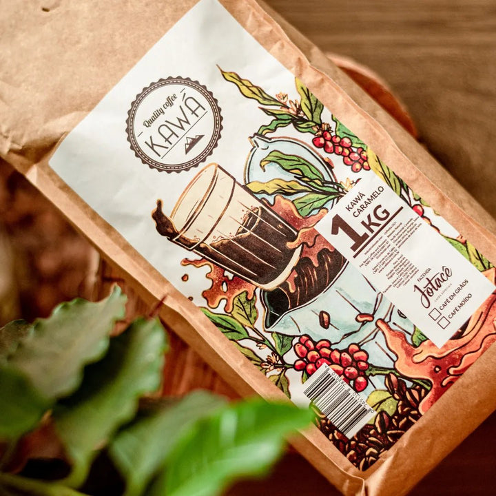 Vista superior de pé de café desfocado e pacote de 1 Kg de Café Kawa Caramelo da Fazenda Jotacê  sobre mesa de madeira