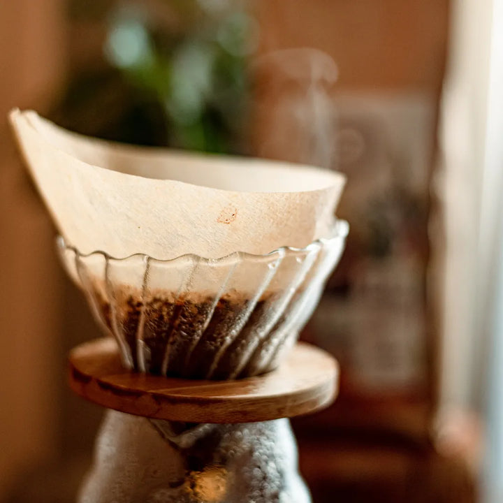 Café sendo extraído em jogo para passar café com Porta filtro de vidro cônico ondulado com base de bambu e jarra de vidro