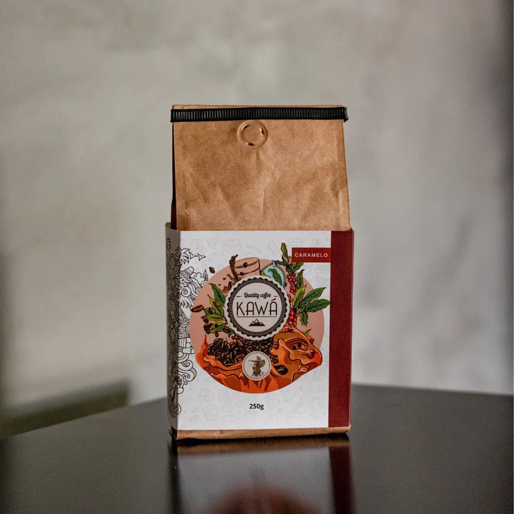 Pacote de 250g do Café naturalmente doce Kawá Caramelo da Fazenda Jotacê, sobre a quina de uma mesa com fundo desfocado