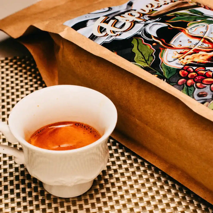 Xícara de espresso ao lado do pacote de Kawá Espresso em superfície texturizada.