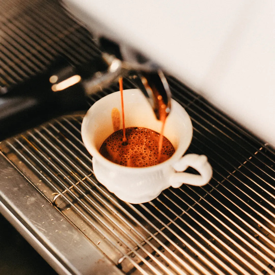 Xícara branca de espresso fresco saindo da máquina de café