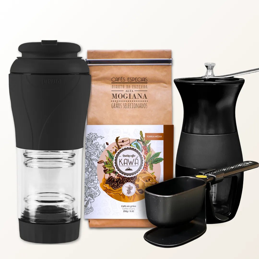 Conjunto para preparo de café com cafeteira portátil, moedor manual, pacote de café e balança, sobre fundo branco.