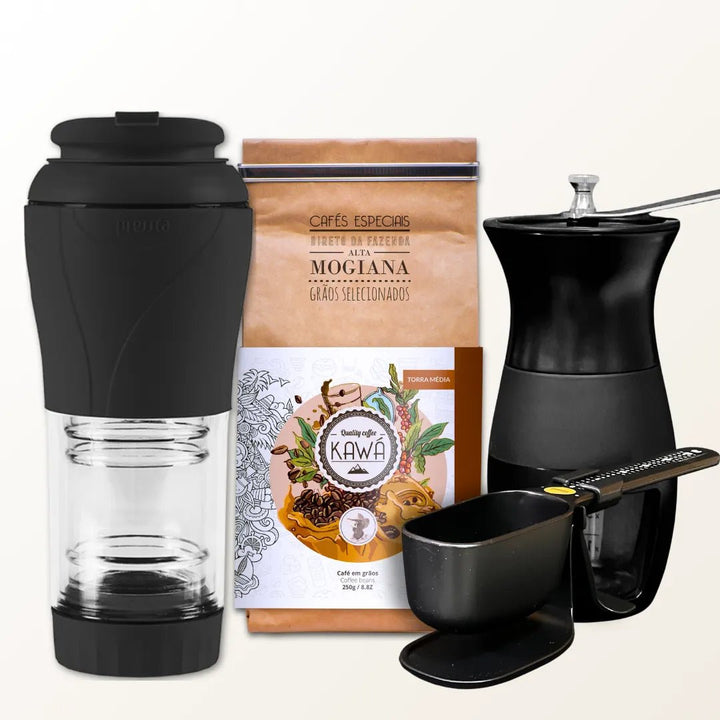 Conjunto para preparo de café com cafeteira portátil, moedor manual, pacote de café e balança, sobre fundo branco.