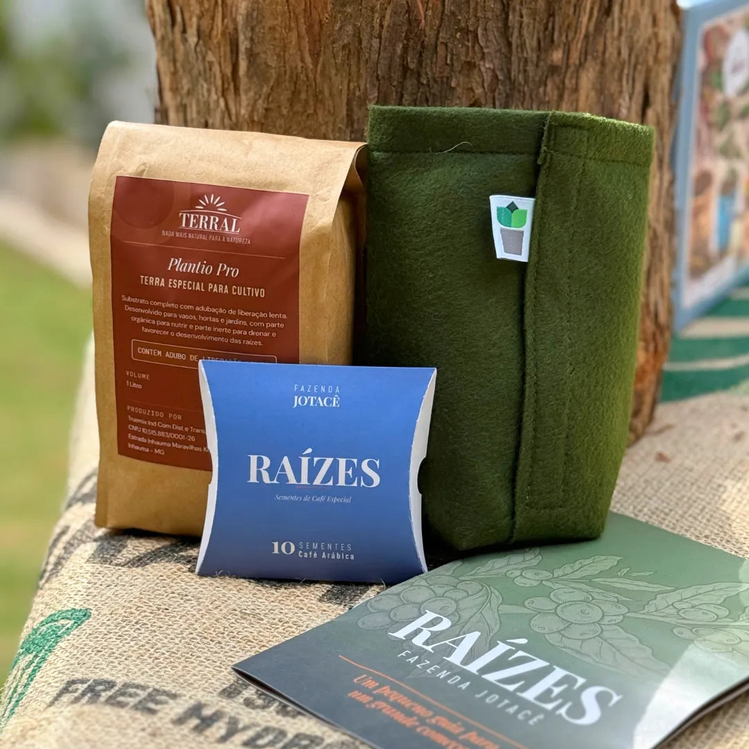 Itens da Coleção Raízes lado a lado sobre saco de juta: pillow box com 10 sementes de café arábica, terra TERRAL Plantio Pro, vaso King Pot e revista guia.
