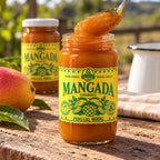 Colher erguendo doce de manga cremoso de um pote de vidro de Mangada Dona Lázara 400g, com outro pote, manga madura e jarra esmaltada sobre mesa de madeira ao sol.