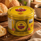 Lata fechada de Manteiga Real com sal sobre mesa de madeira rústica, mostrando a tampa amarela "sem corante" e o rótulo, com pães artesanais e uma xícara de café ao lado.