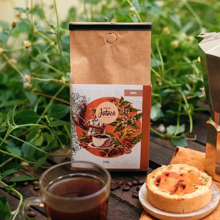 Café Microlote Moca em embalagem estilizada ao lado de xícara e bolo.
