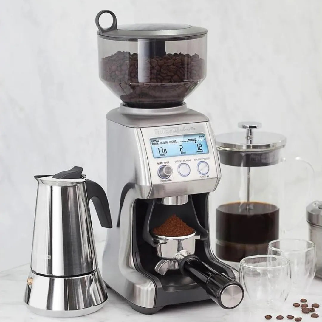 "Moinho de café elétrico com acessórios para preparo de café, incluindo cafeteira e jarra, sobre balcão de mármore.