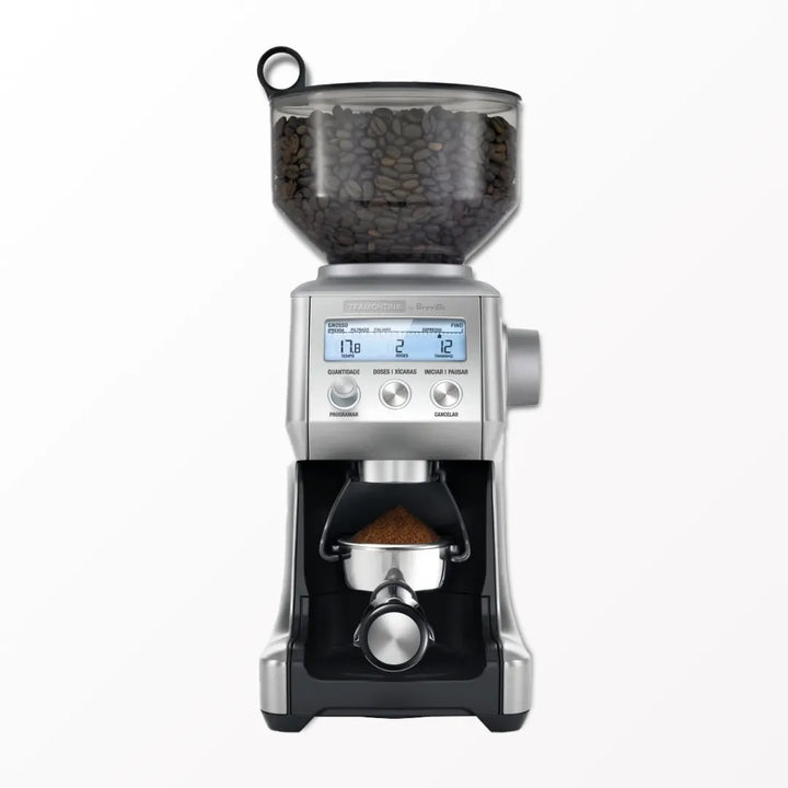 Moinho de café elétrico da Tramontina Breville com grãos de café e display digital, sobre fundo branco.