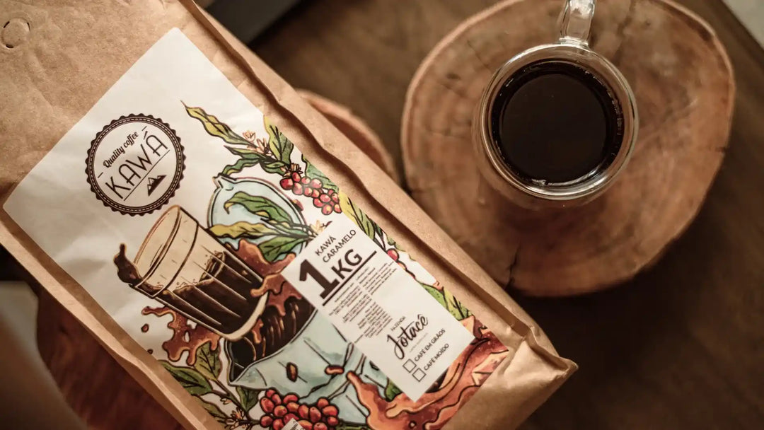 Pacote de Café Kawá Caramelo ao lado de uma xícara de café, sobre mesa de madeira.