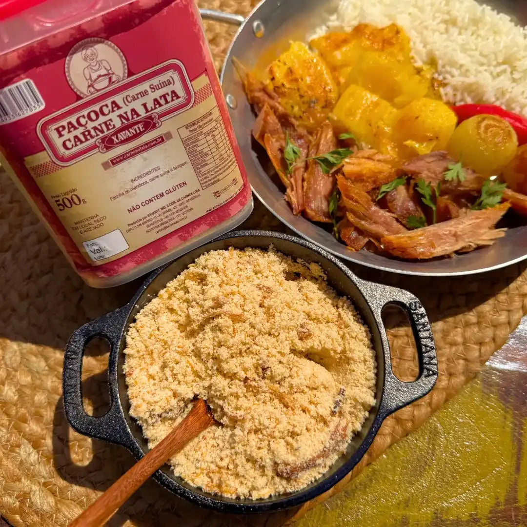 Close da paçoca de carne na lata Xavante em panelinha de ferro, mostrando a textura da farinha de mandioca grossa misturada com pedaços de carne suína desfiada.