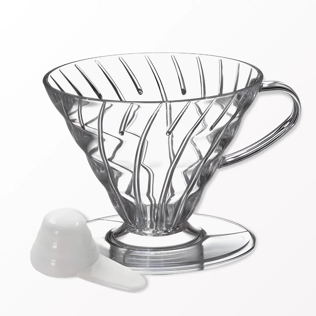 Porta Filtro cônico para café na cor transparente ao lado de uma colher dosadora com fundo branco
