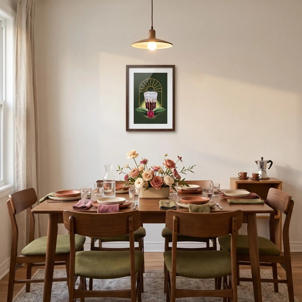 Quadro decorativo do copo de café na parede de uma sala de jantar, sobre mesa de madeira posta com pratos de cerâmica, arranjo de flores e cafeteira italiana ao lado.