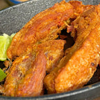 Pedaços de Torresmo Especial Xavante 900g servidos em frigideira de ferro com limão, prontos pra comer, com a casquinha dourada característica.
