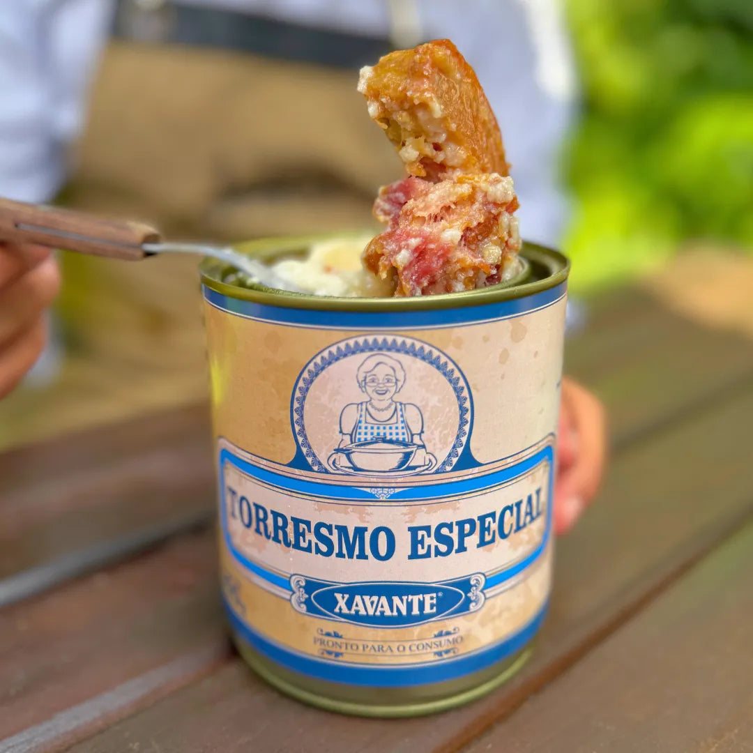 Lata aberta de Torresmo Especial Xavante com pedaço da carne de lata sendo retirado no garfo, mostrando o produto envolto na própria banha.