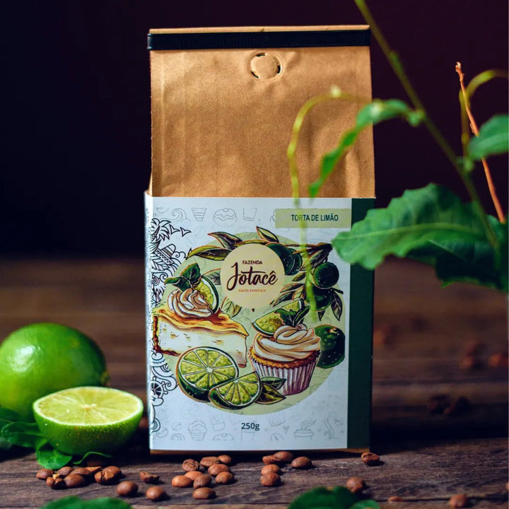 Em primeiro plano uma muda de pé de limão e no fundo um pacote do café torta de limão com limão cortado ao lado