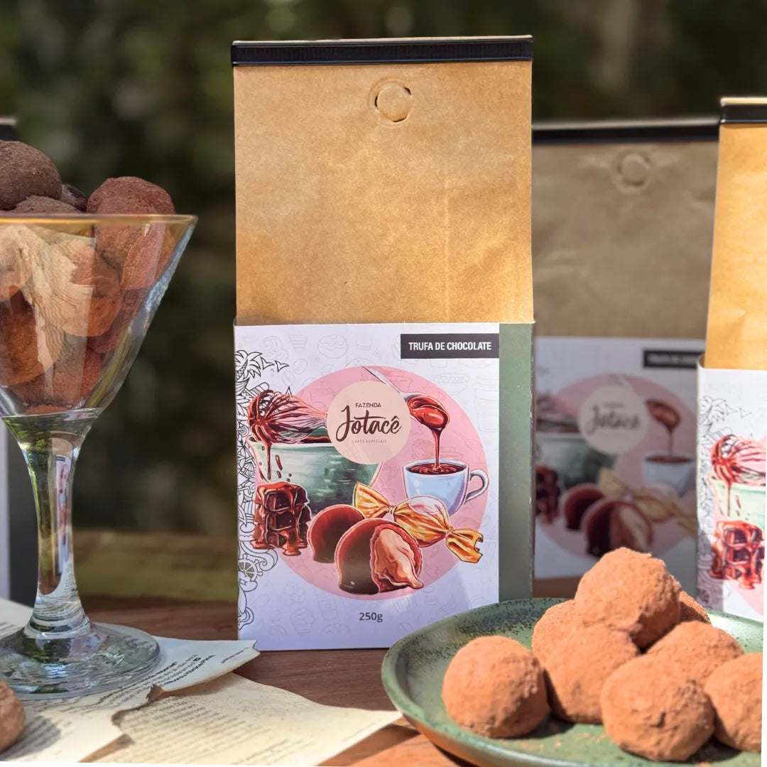Três embalagens de Café Trufa de Chocolate 250g ao lado de trufas polvilhadas em cacau