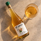 Garrafa do Laranjinha Cão Perdigueiro deitada ao lado de uma taça, vista de cima, em piso de cimento claro